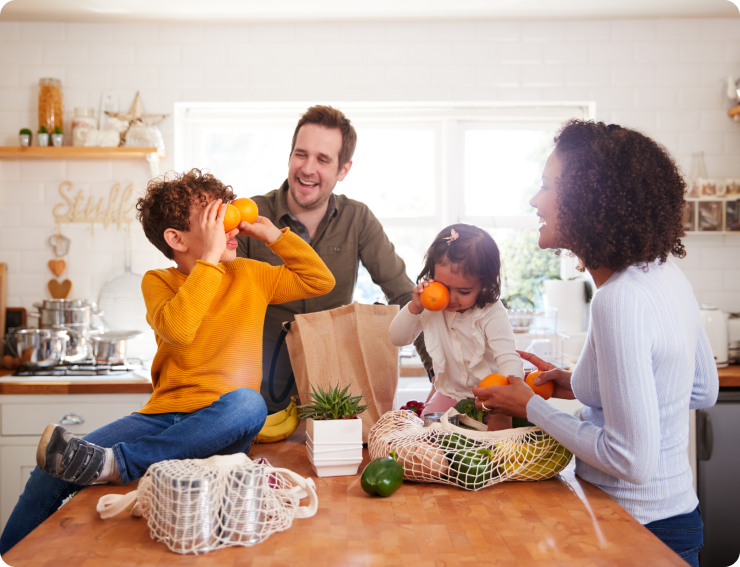 Children with Oranges, Mom, dad, and two children in the kitchen unpacking grocery bags together
